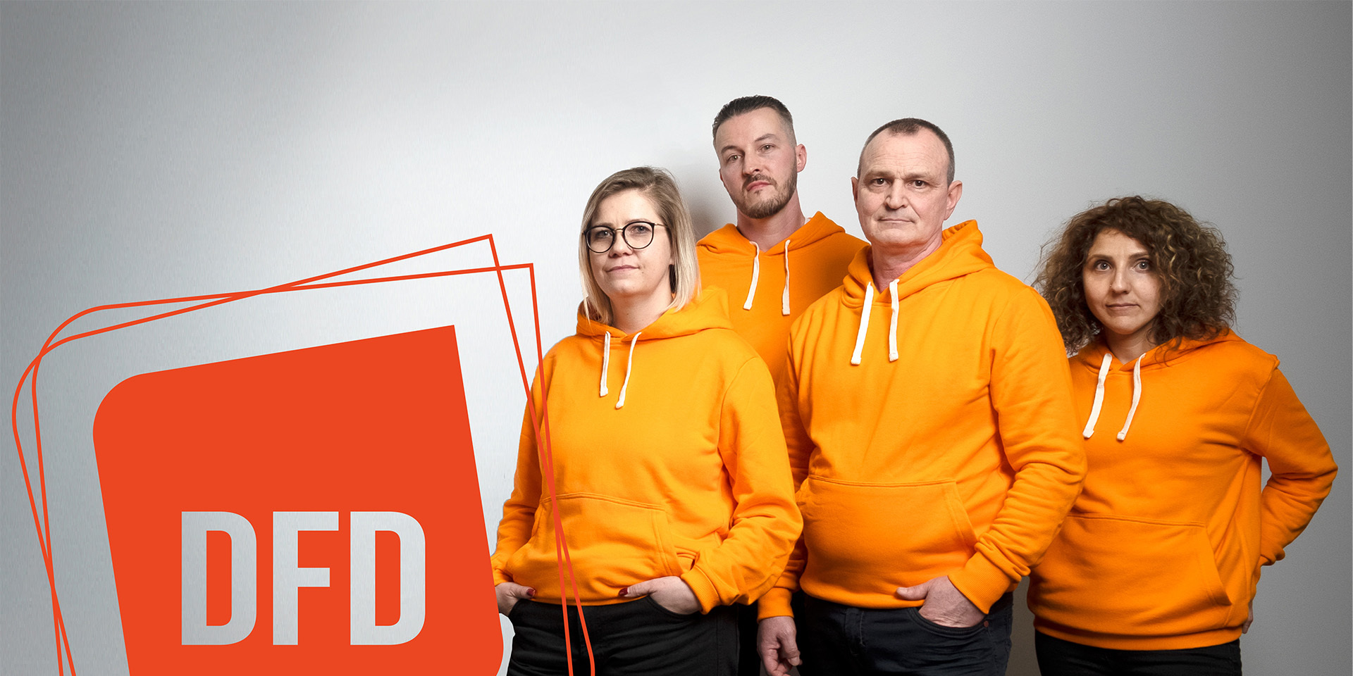 Team von DFD in orangefarbenen Hoodies, bereit für die Zukunft des Retailgeschäfts.  Karriere bei DFD: Gemeinsam für Omnichannel-Lösungen.