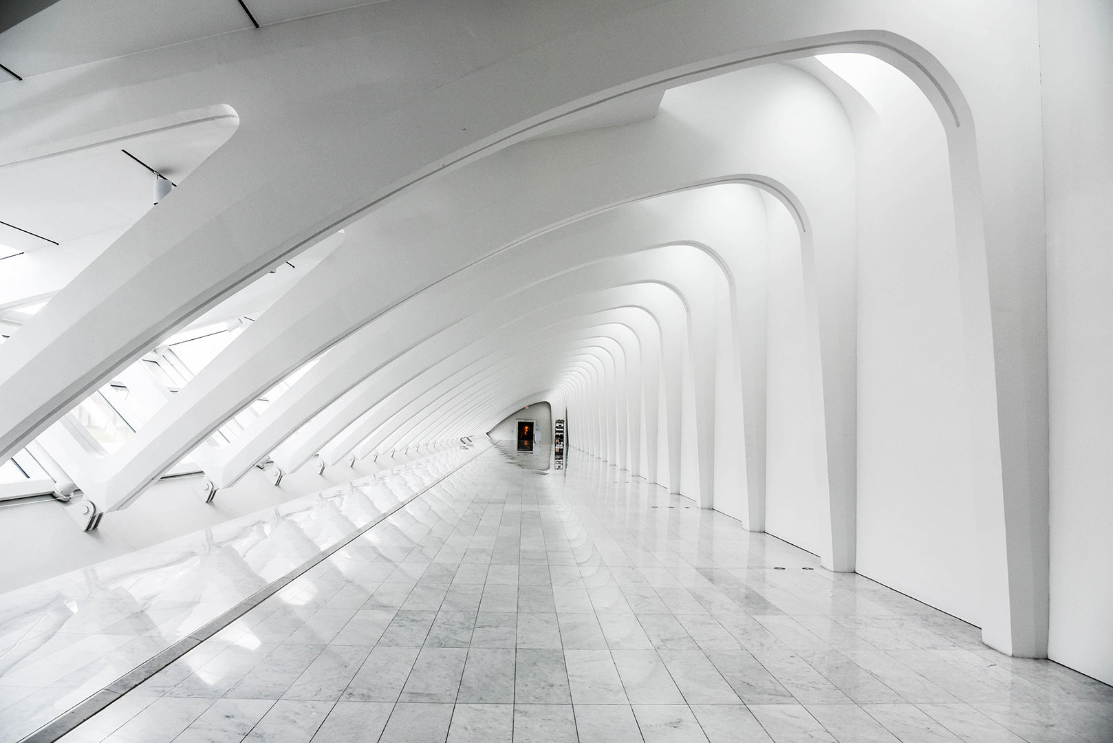 Weißer, futuristischer Gang mit gewölbten Decken und hellem Marmorboden, Symbol für die Zukunft des Einzelhandels.  Ein architektonisches Meisterwerk, das unsere Vision von nahtloser Omnichannel-Integration repräsentiert.