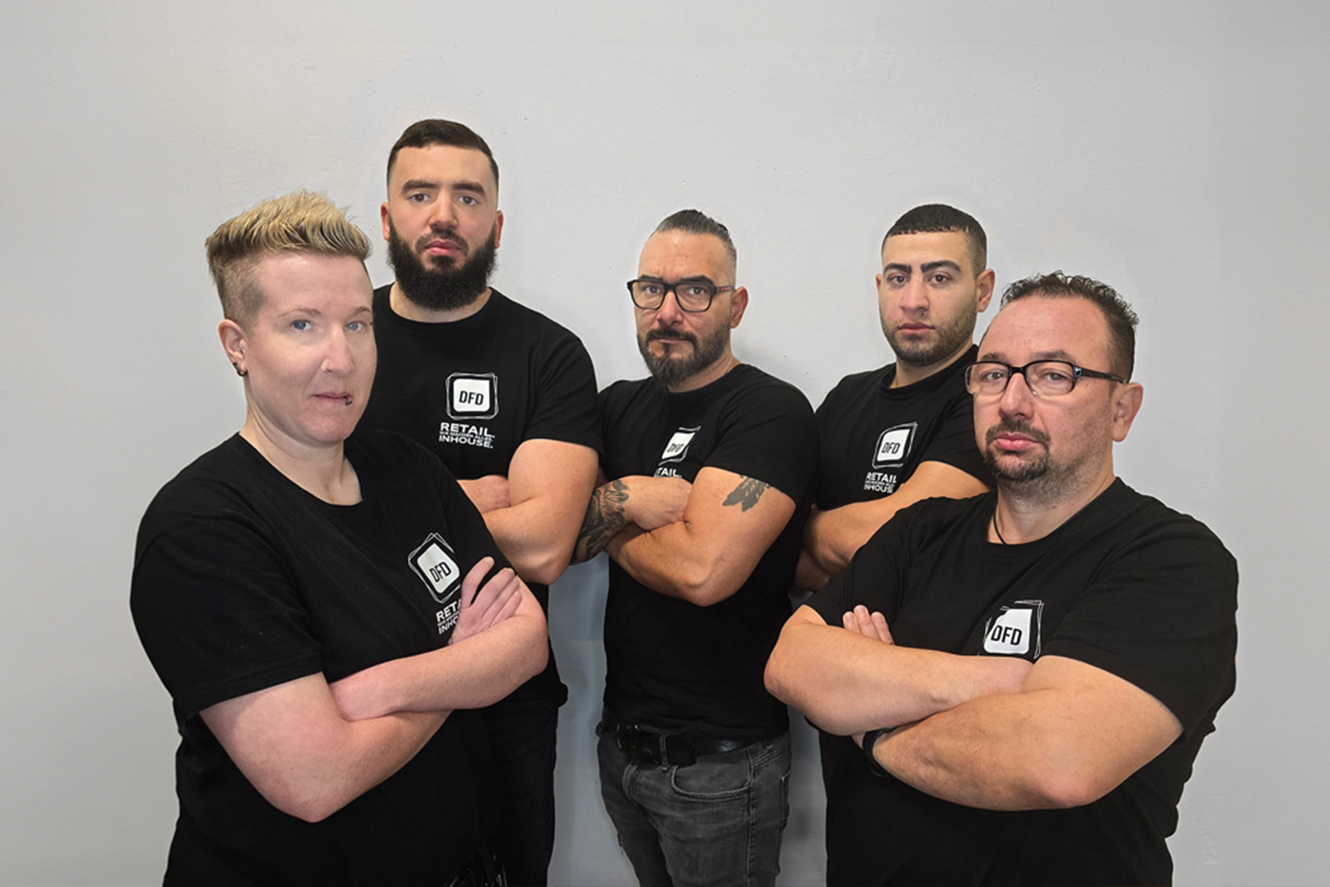 Team von DFD Retail Inhouse, bereit für die Zukunft des Einzelhandels. Das Team steht mit verschränkten Armen vor neutralem Hintergrund.
