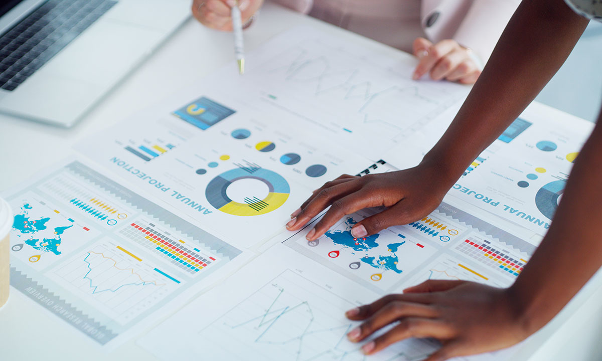 Teamwork bei der Analyse von Retail-Daten und Diagrammen, um das Retailgeschäft der Zukunft zu gestalten.  Die Hände auf den Diagrammen zeigen die strategische Planung für Omnichannel-Lösungen.