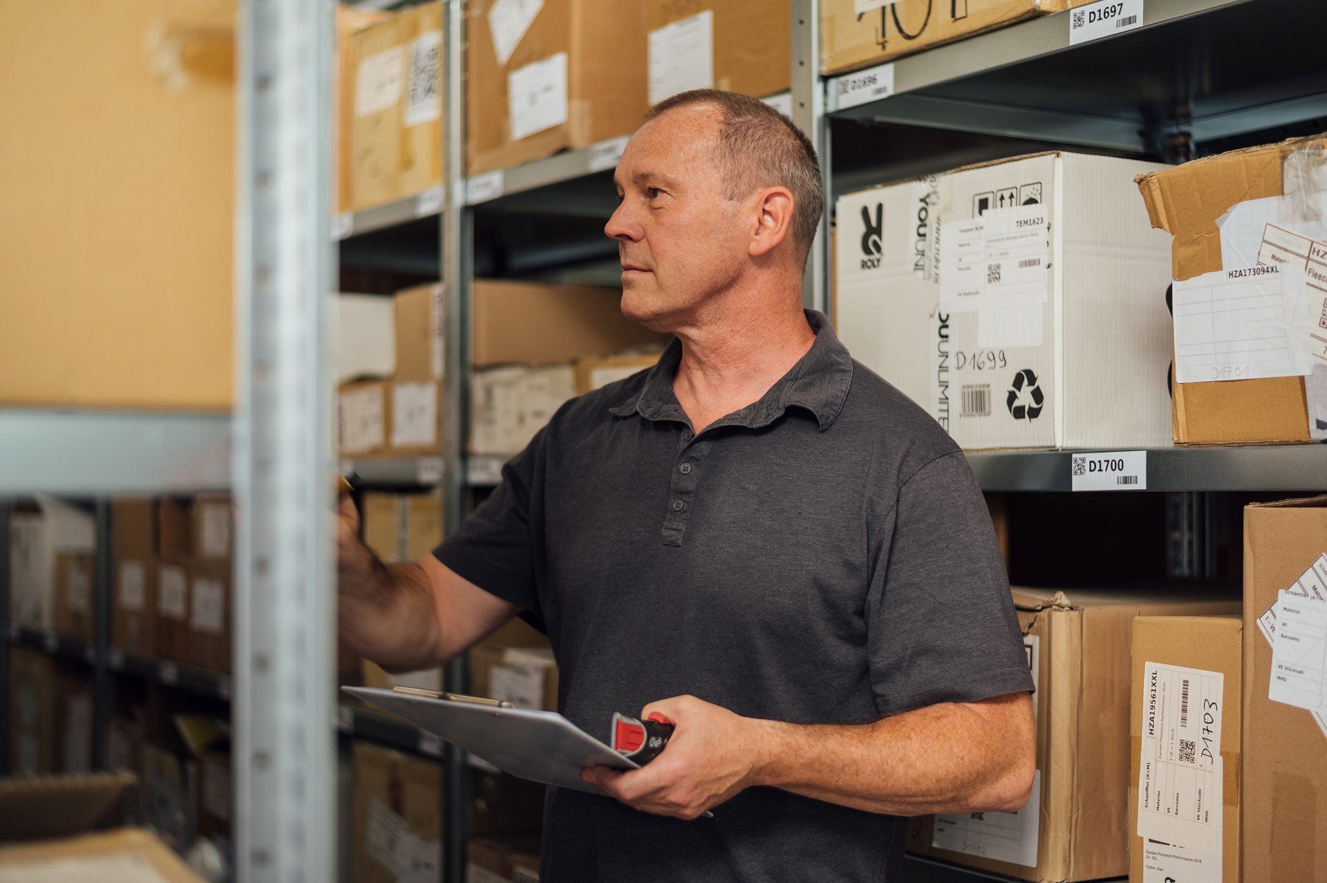 Mitarbeiter im Lager prüft Waren. Bild für Karriere-Seite des Unternehmens, das Omnichannel-Lösungen für den Einzelhandel anbietet.