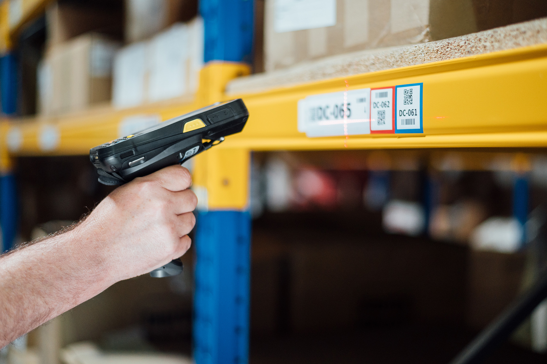 Handscanner beim Scannen von QR-Codes in einem Lager.  Diese Technologie unterstützt die Omnichannel-Verknüpfung im Einzelhandel.