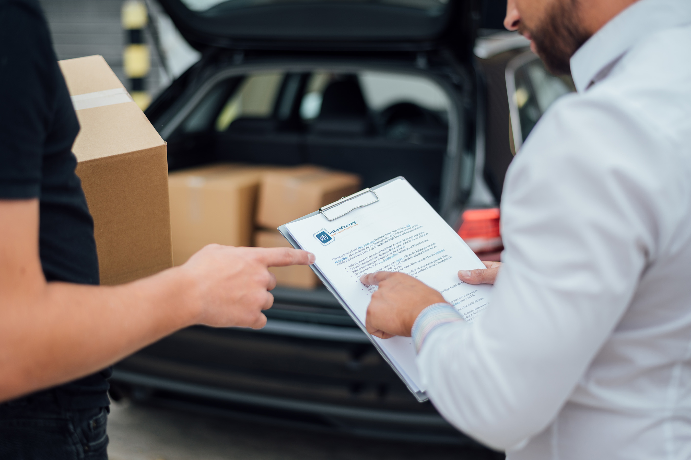 Zwei Mitarbeiter prüfen Lieferdokumente neben einem Lieferwagen, um ein nahtloses Omnichannel-Erlebnis zu gewährleisten.  Die Szene zeigt die moderne Logistiklösungen von dfd.
