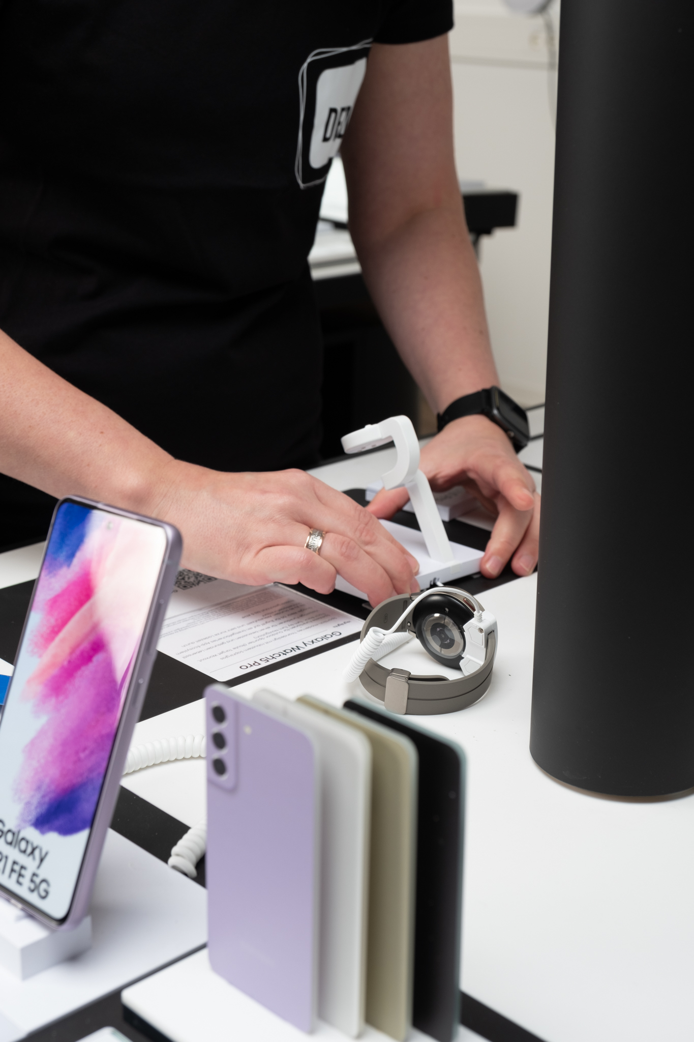 Mitarbeiter präsentiert Smartphones und Smartwatch am POS, Teil der Omnichannel-Strategie.  Das Bild zeigt unsere Vision für das Retailgeschäft der Zukunft.