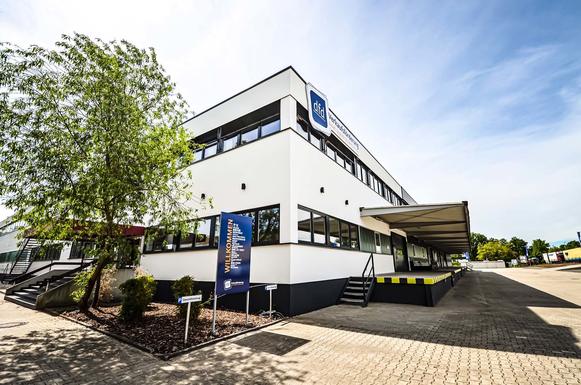 dfd-Firmengebäude mit Willkommensschild. Das Bild zeigt das Bürogebäude von dfd, einem Unternehmen für Verkaufsförderung.