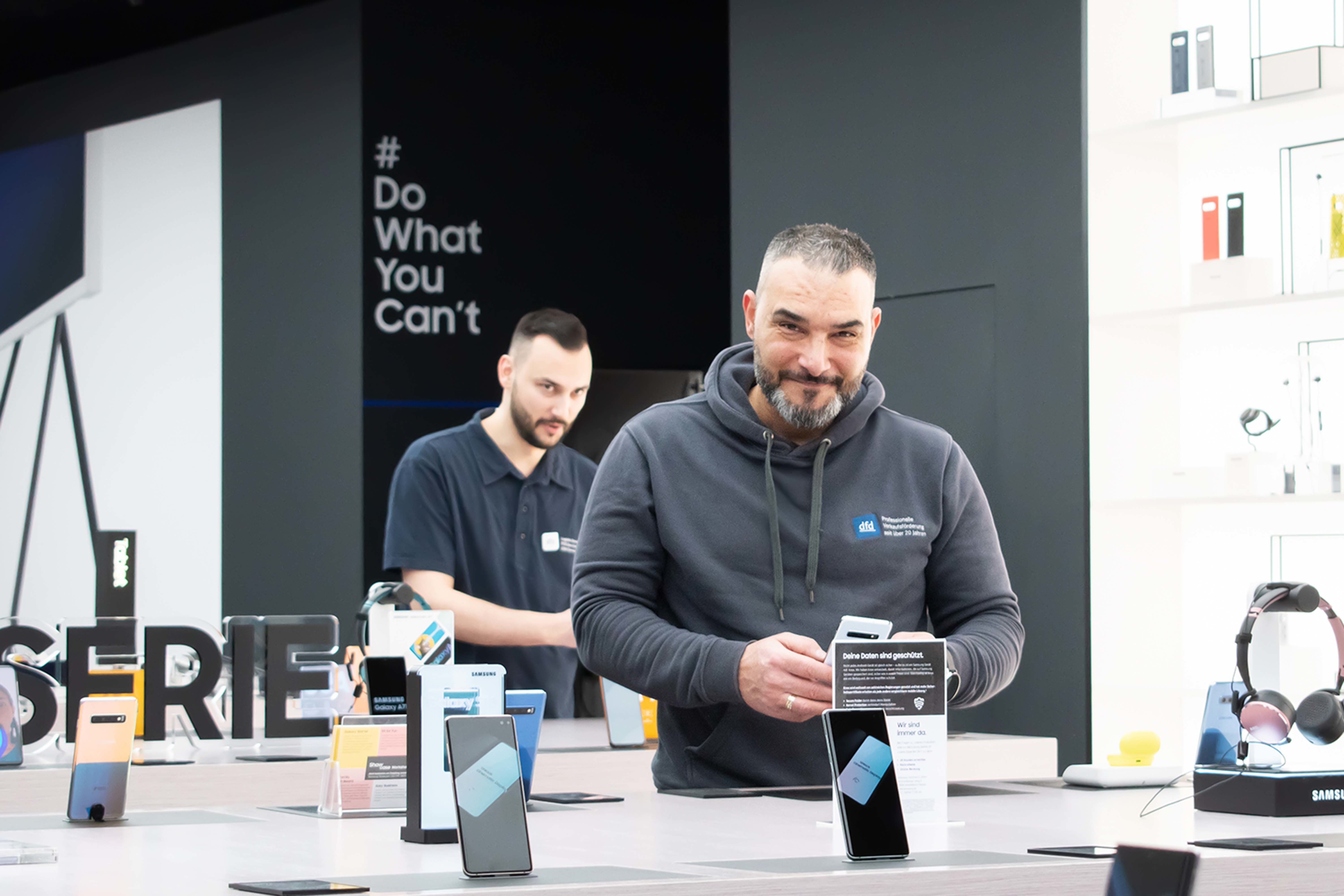 Mitarbeiter präsentiert Smartphones in einem modernen Retail-Geschäft. Die Bild zeigt die Zukunft des Einzelhandels mit Omnichannel-Verknüpfung.