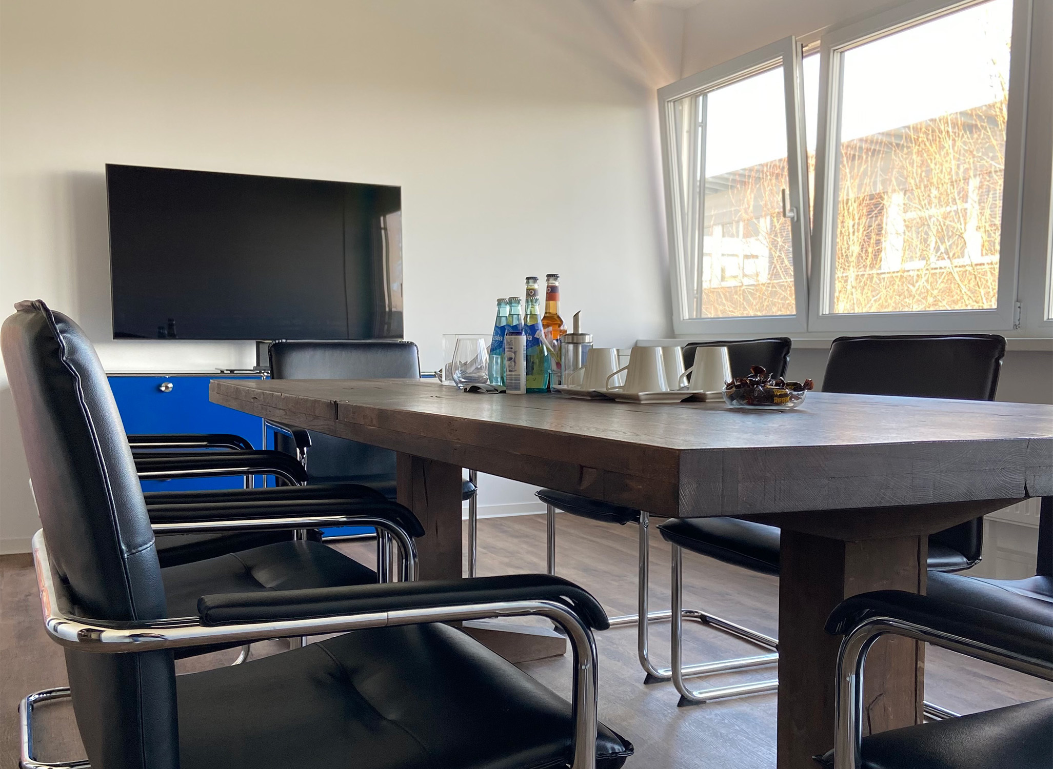 Konferenzraum mit modernem Design, ideal für die Zusammenarbeit und die Zukunft des Einzelhandels. Der Raum ist mit einem Tisch, Stühlen und einem Bildschirm ausgestattet.