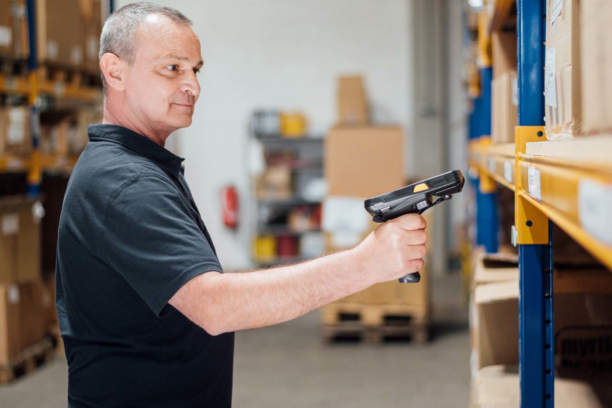 Mitarbeiter im Lager mit einem Scanner, der die Omnichannel-Verknüpfung für das Retailgeschäft der Zukunft unterstützt.  Effiziente Logistik für den Einzelhandel.