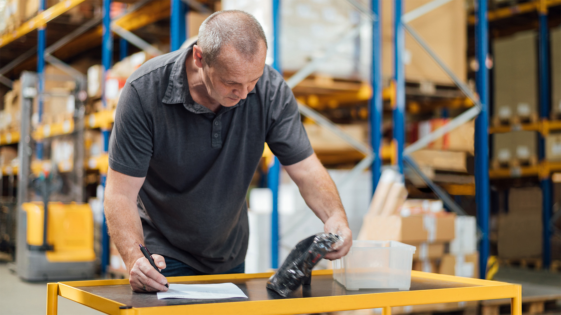 Logistikmitarbeiter bei der Arbeit in einem Lager, das die Zukunft des Einzelhandels unterstützt. Der Mann notiert Informationen mit einem Stift.