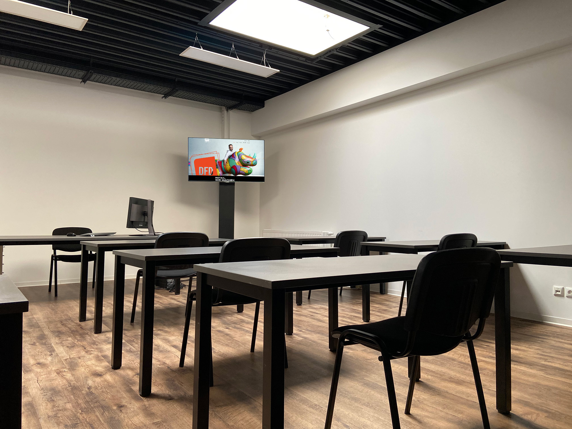 Modernes Büro mit Tischen und Stühlen, ideal für die Entwicklung von Retail-Lösungen. Im Hintergrund ein Bildschirm mit dem Slogan 