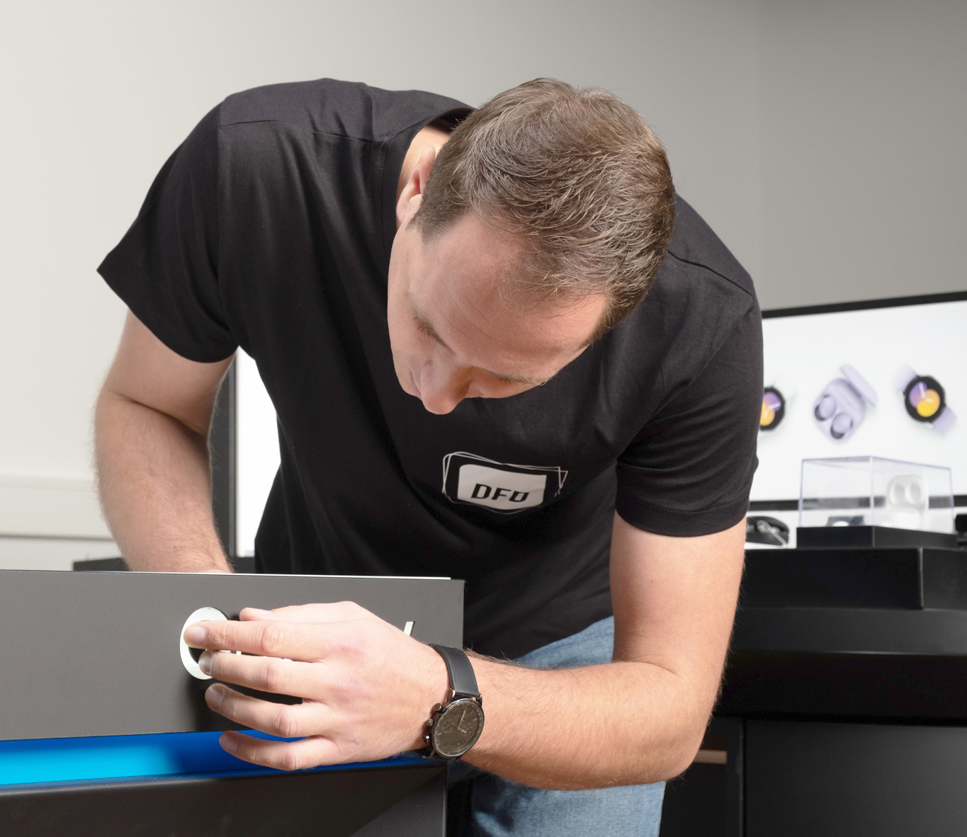 Ein Mitarbeiter von DFD bei der Arbeit an einem Projekt zur Gestaltung des Einzelhandels der Zukunft. Der Mann trägt ein DFD-T-Shirt und arbeitet an einem Gerät.